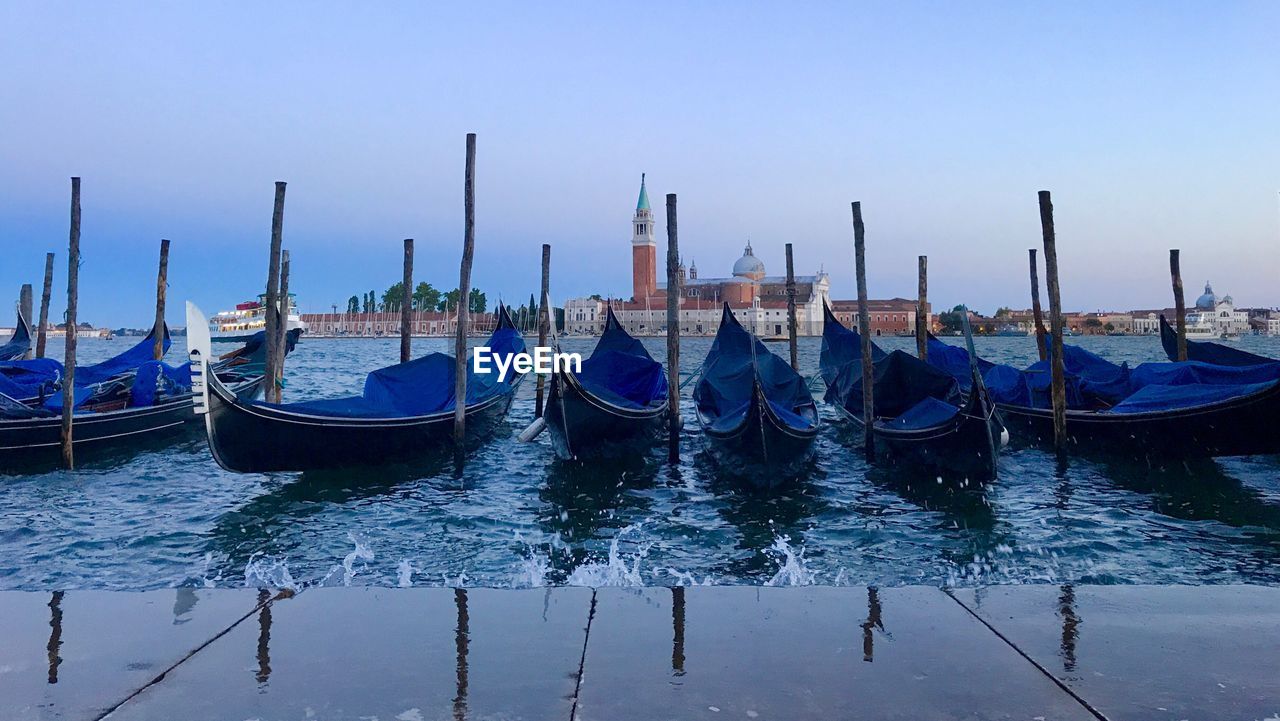 Boats moored in canal against clear sky