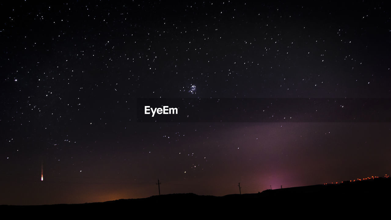 Meteor and star field over landscape at night