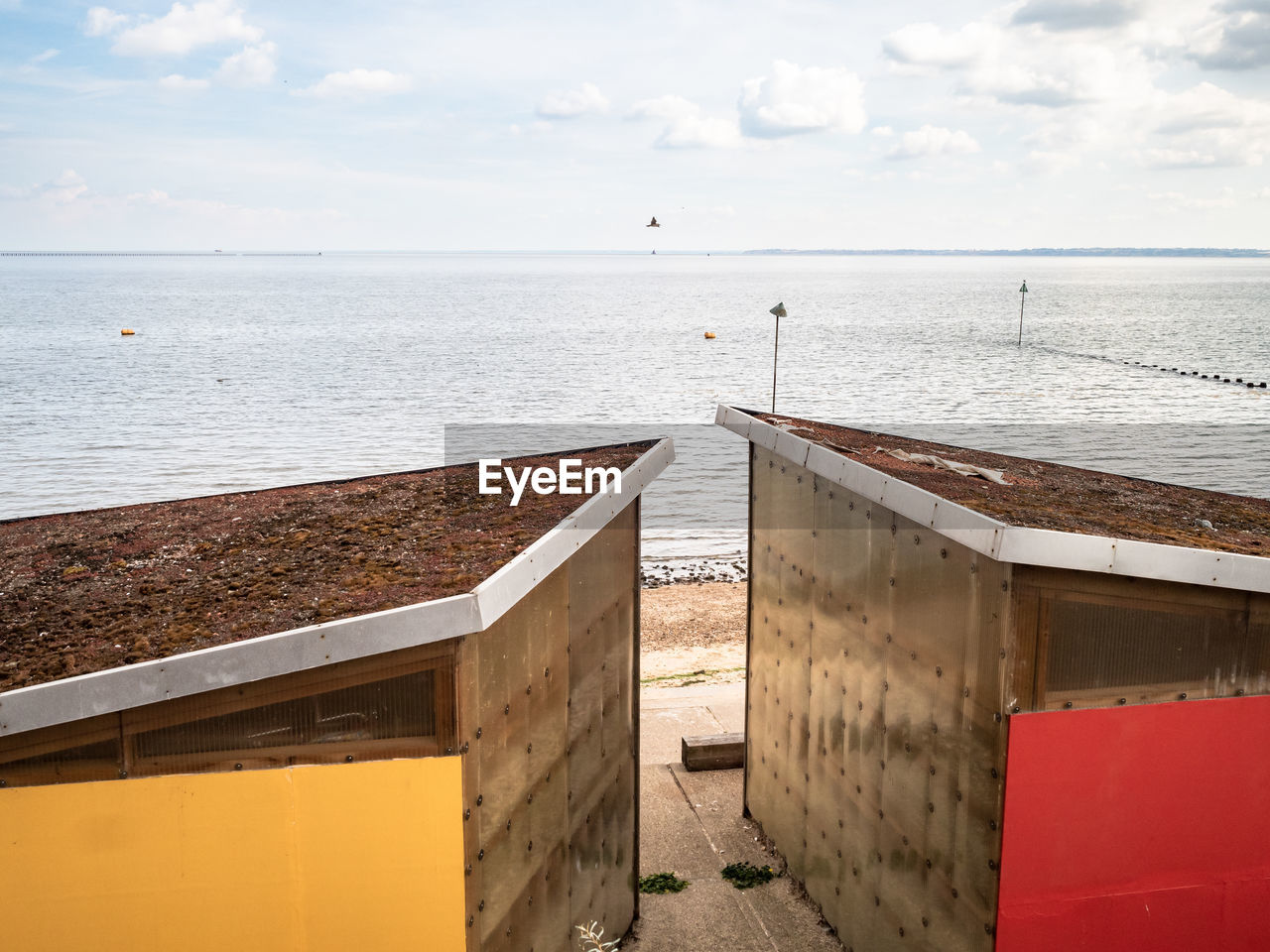 Beach huts with living roofs, and red and yellow panels on the beach at shoeburyness