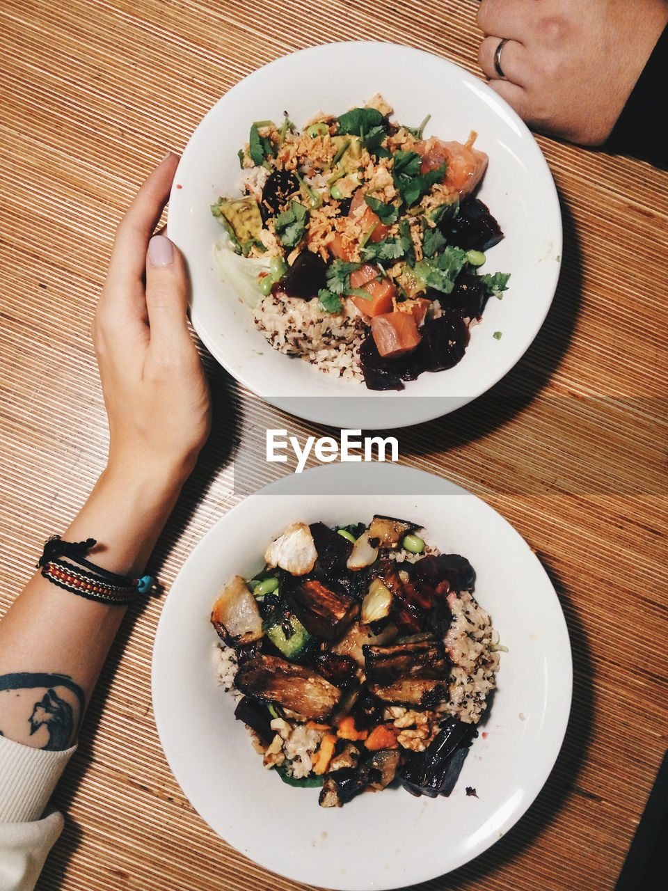 High angle view of person hand on table with salad bowl