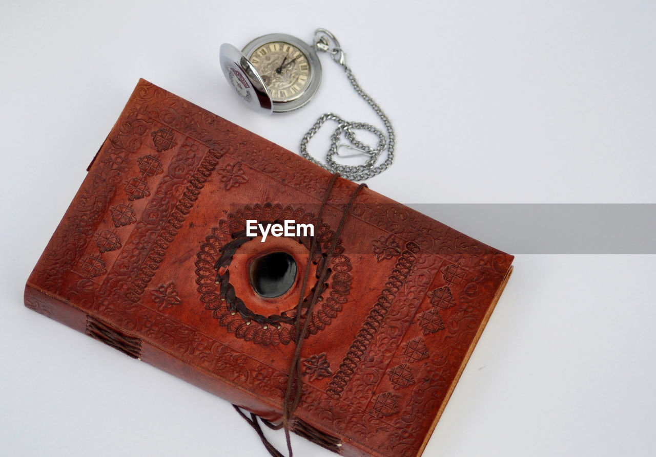Close-up of book and pocket watch against white background