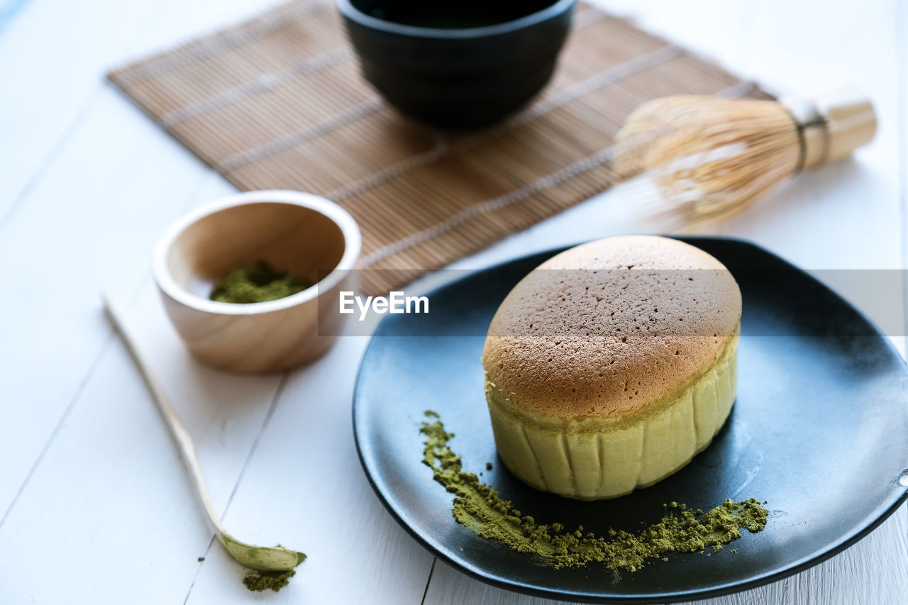 Matcha japanese cheesecake and matcha green tea on white desk table in morning, close up.