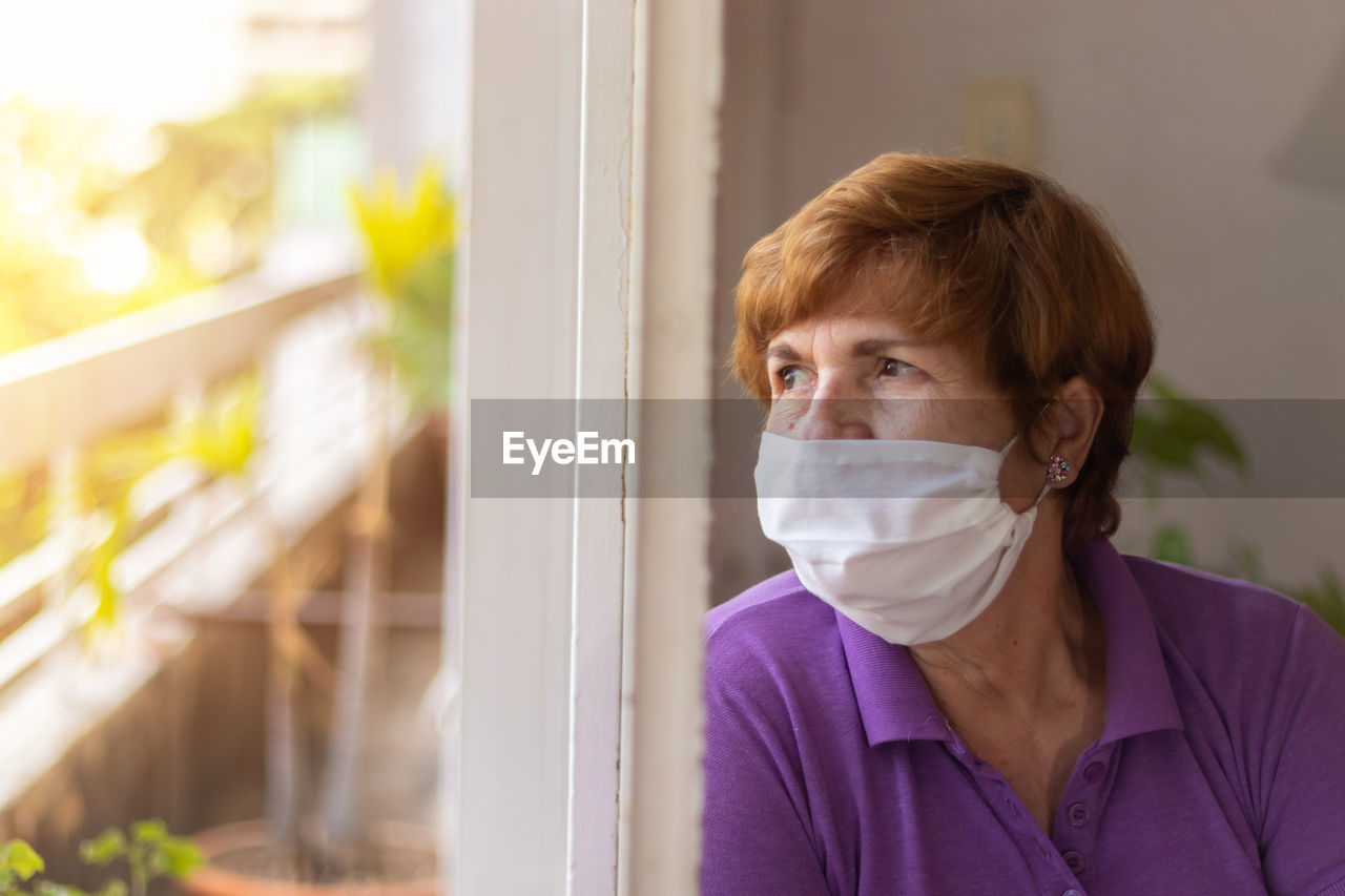 Elderly watches through the window of her house, while being confined by the coronavirus quarantine.....