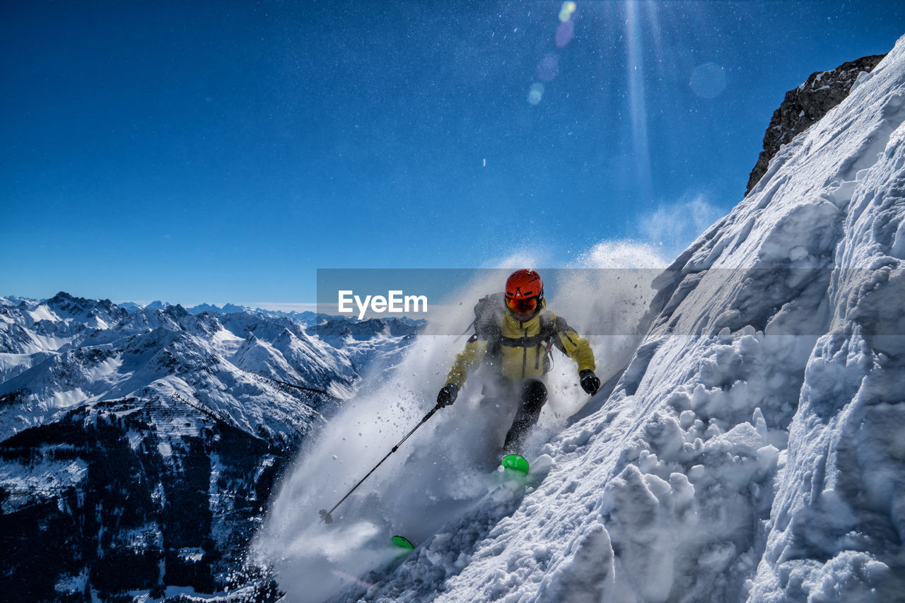 Woman skiing on snowcapped mountain against sky