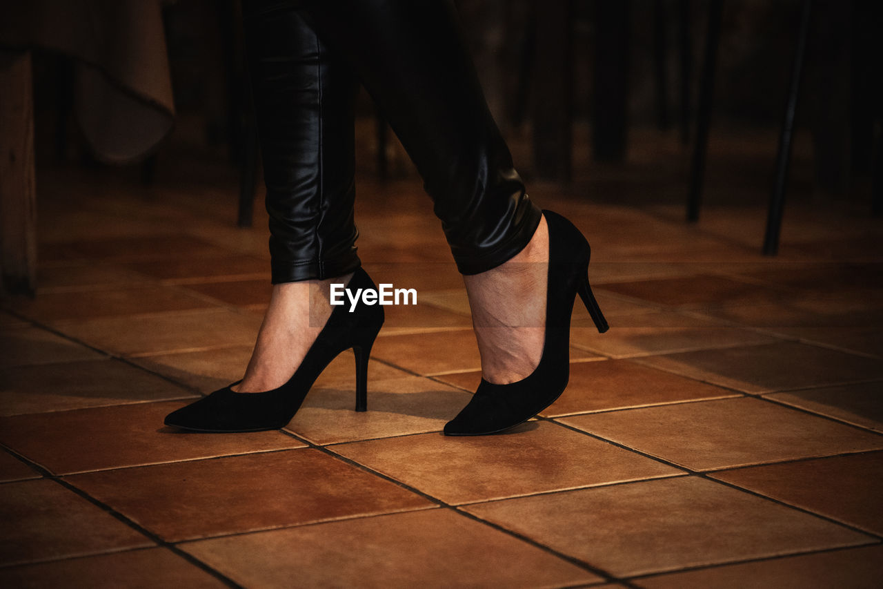 Low section of woman wearing high heels standing on tiled floor