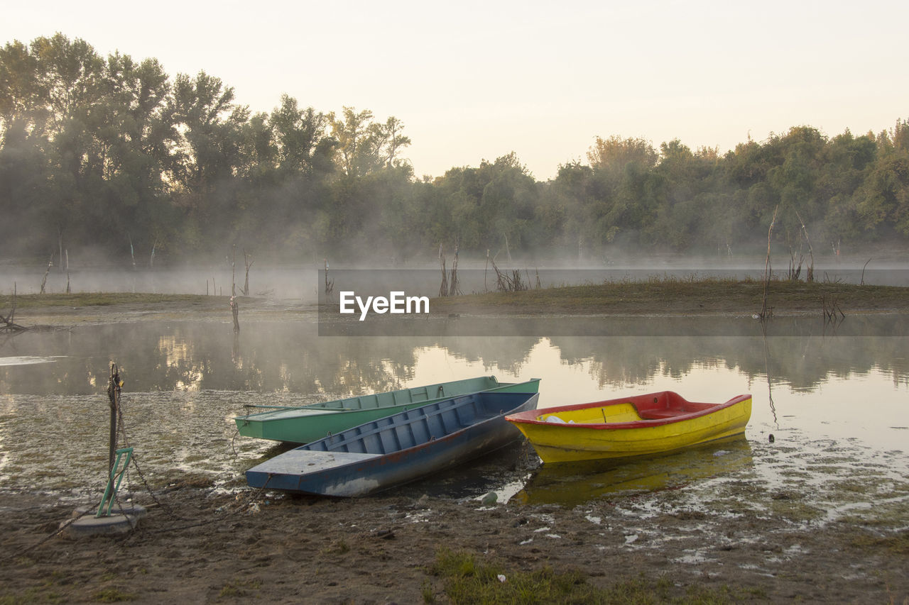 BOAT MOORED ON LAKE AGAINST SKY