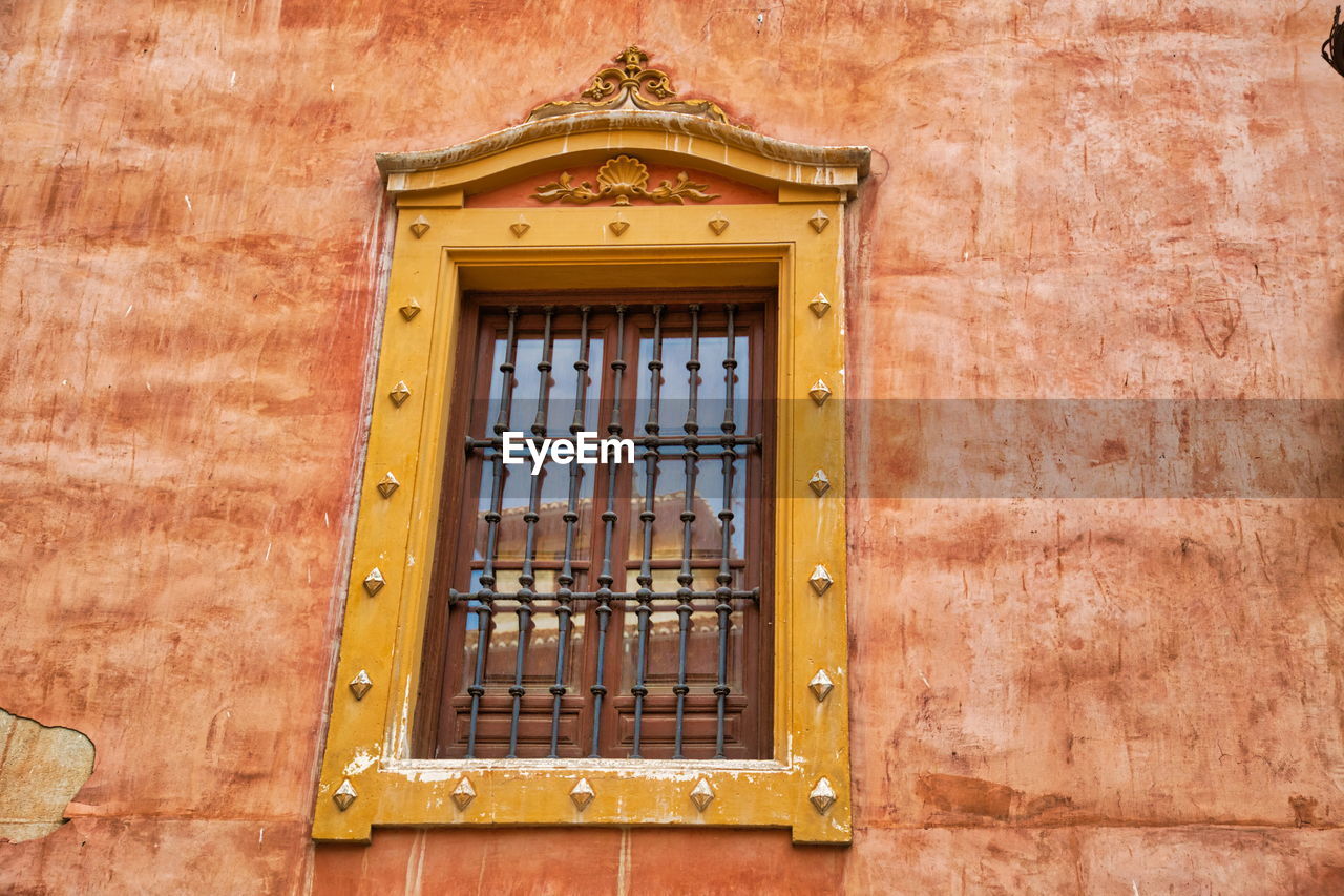 LOW ANGLE VIEW OF YELLOW WINDOW ON BUILDING