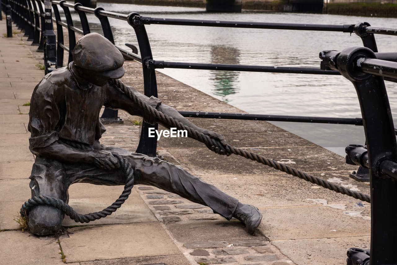 water, railing, architecture, day, iron, statue, full length, nature, sculpture, outdoors, metal, person, footpath, city, street, men
