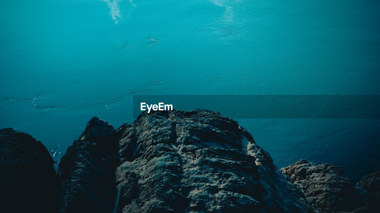 HIGH ANGLE VIEW OF ROCK FORMATIONS AT SEA