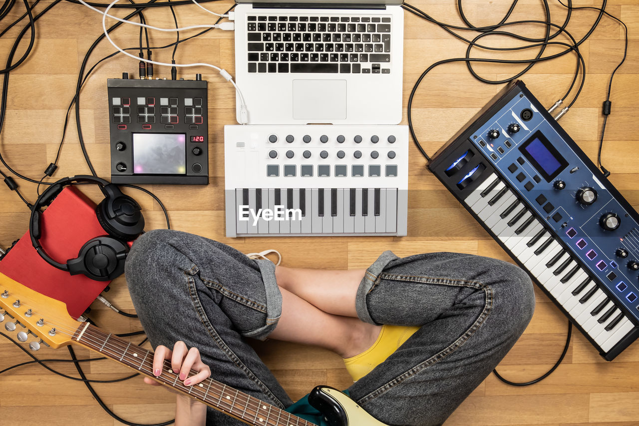 Low section of woman playing guitar while sitting on floor