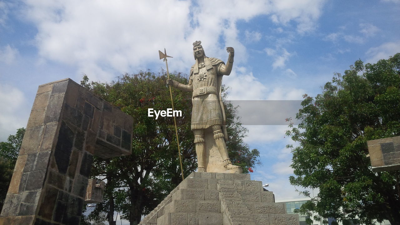 LOW ANGLE VIEW OF STATUES AGAINST CLOUDY SKY