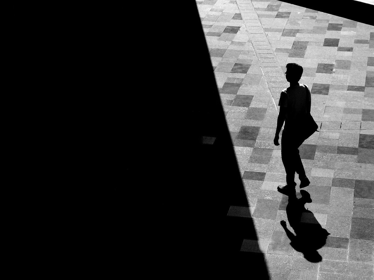 High angle view of man walking on footpath during sunny day