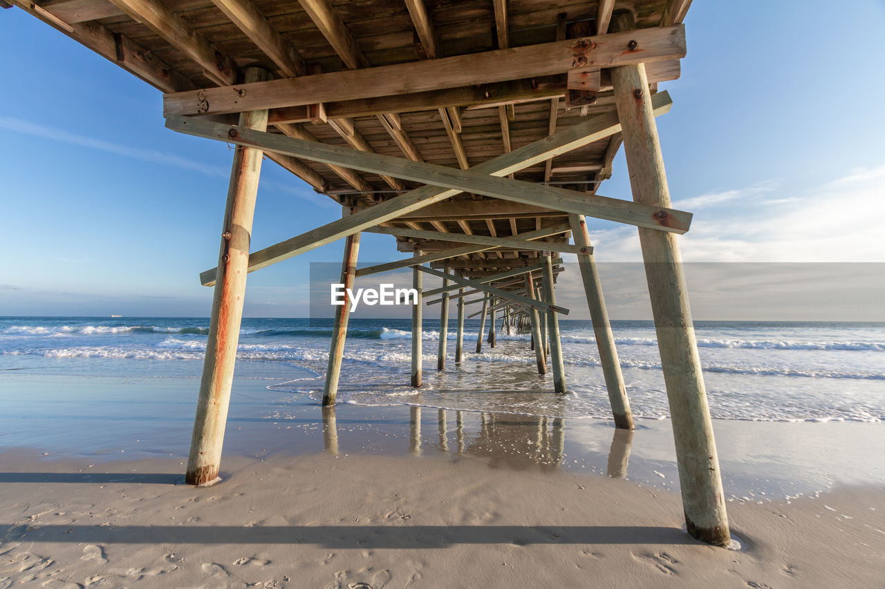 View of pier on beach against sky