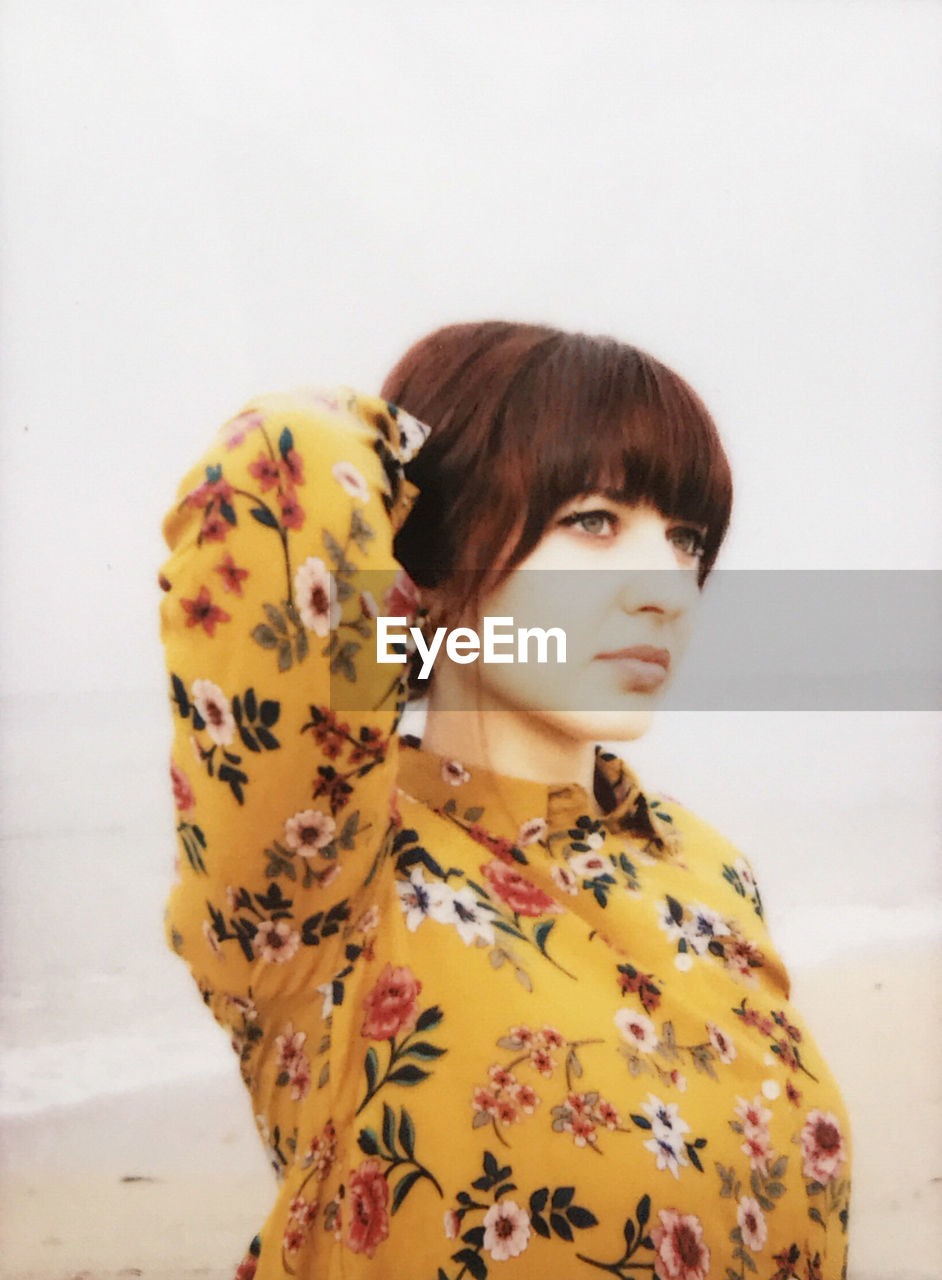 Young woman looking away against clear sky