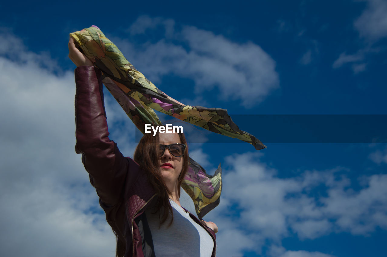 LOW ANGLE VIEW OF WOMAN HOLDING BLUE SKY