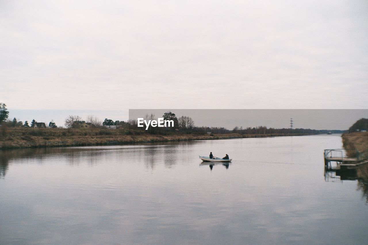 BOATS SAILING ON RIVER AGAINST SKY
