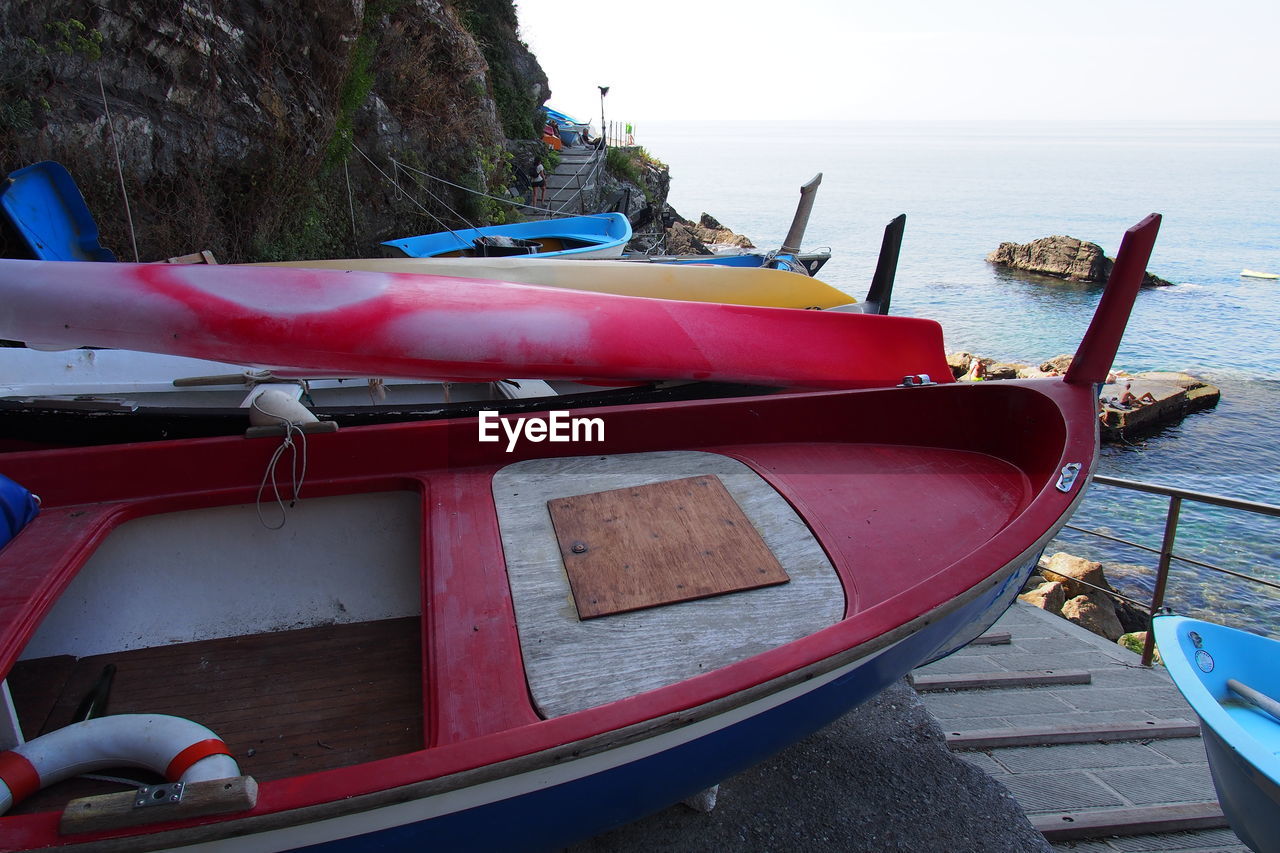 Stack of boats on shore against calm sea