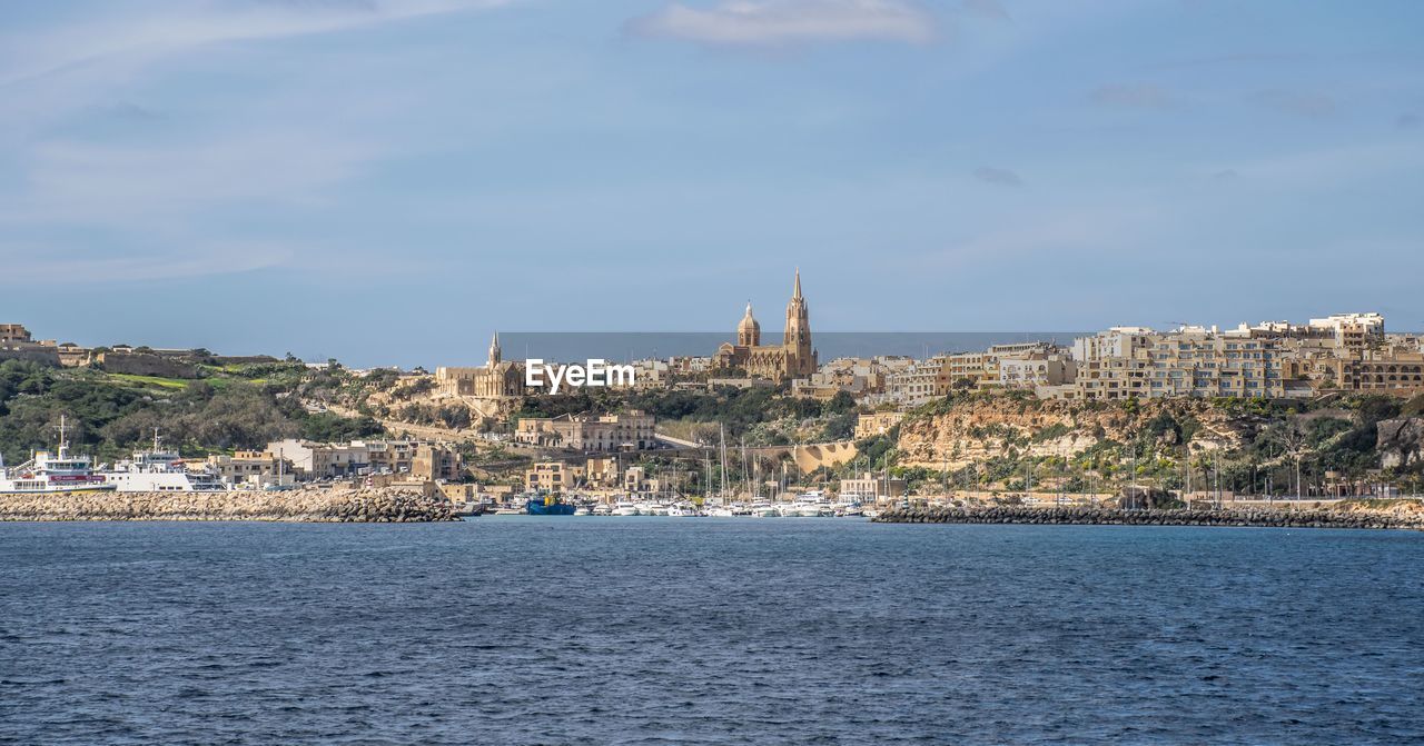 View of city by sea against sky