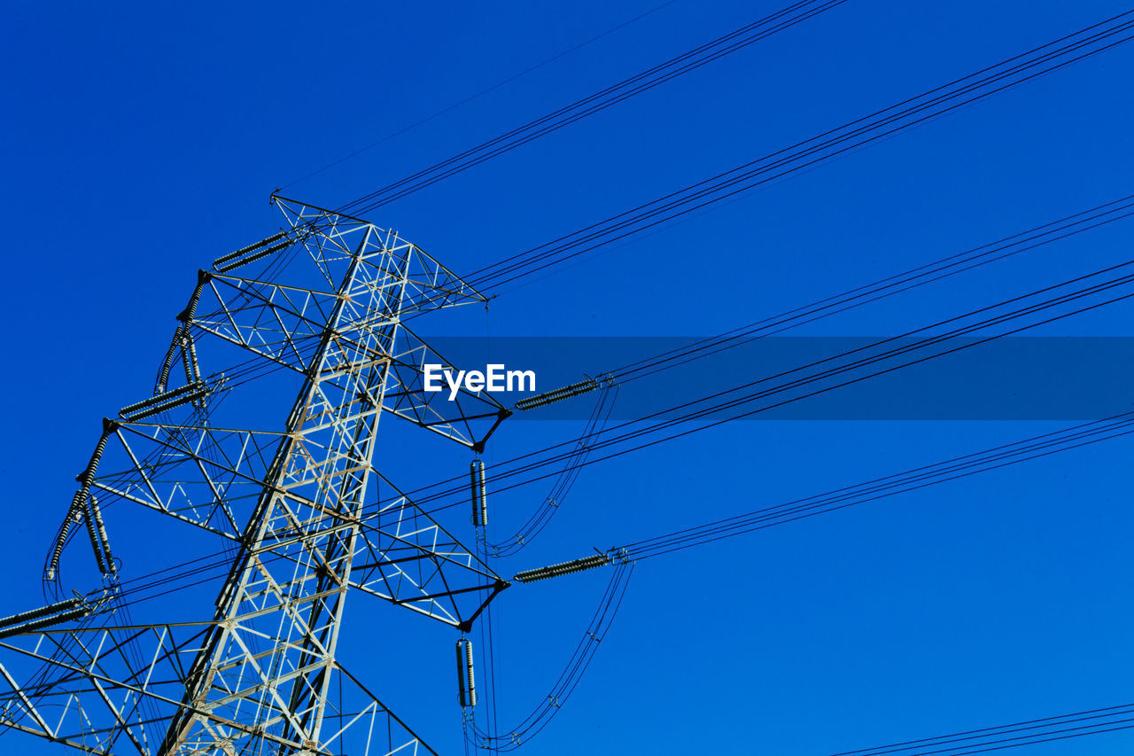 LOW ANGLE VIEW OF ELECTRICITY PYLONS AGAINST CLEAR BLUE SKY