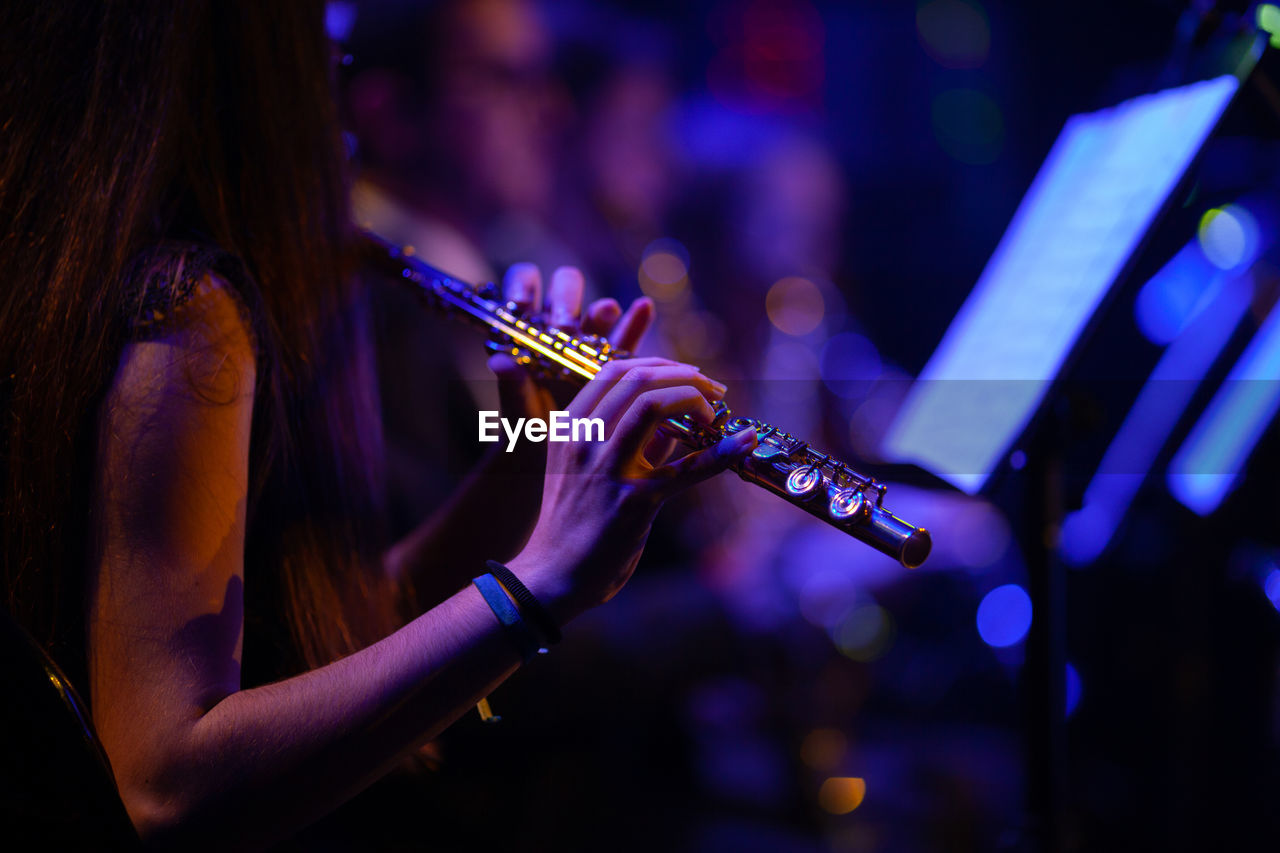 Midsection of woman playing flute in music concert