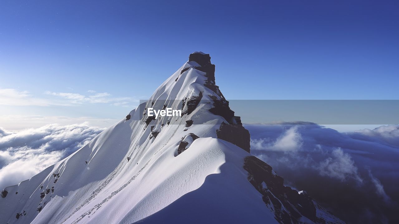 Scenic view of snowcapped mountains against blue sky