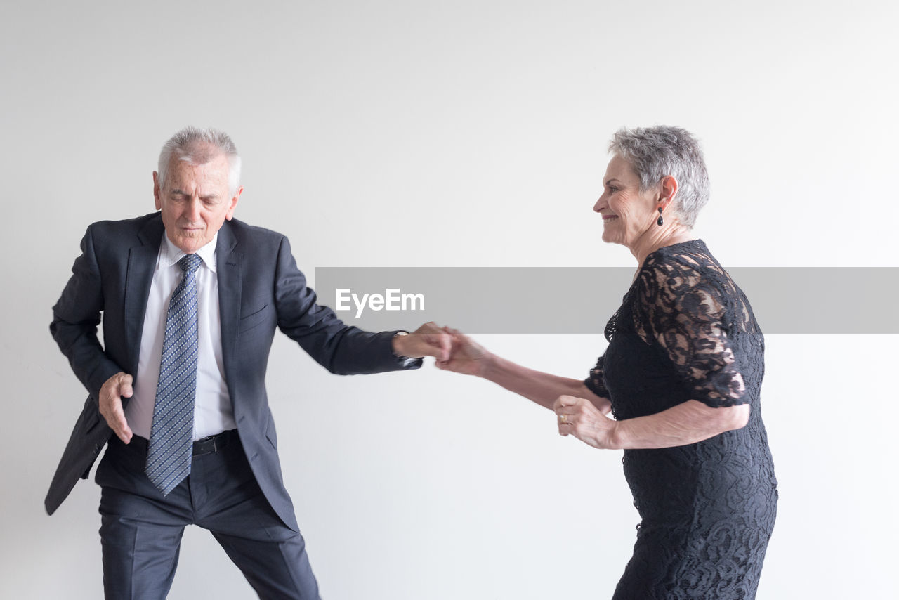 Senior couple dancing against white background