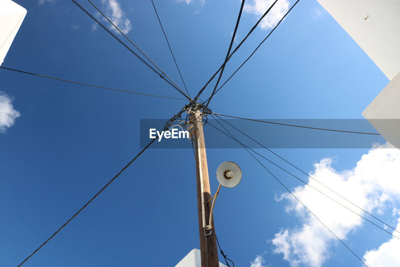 Low angle view of electricity pylon against blue sky