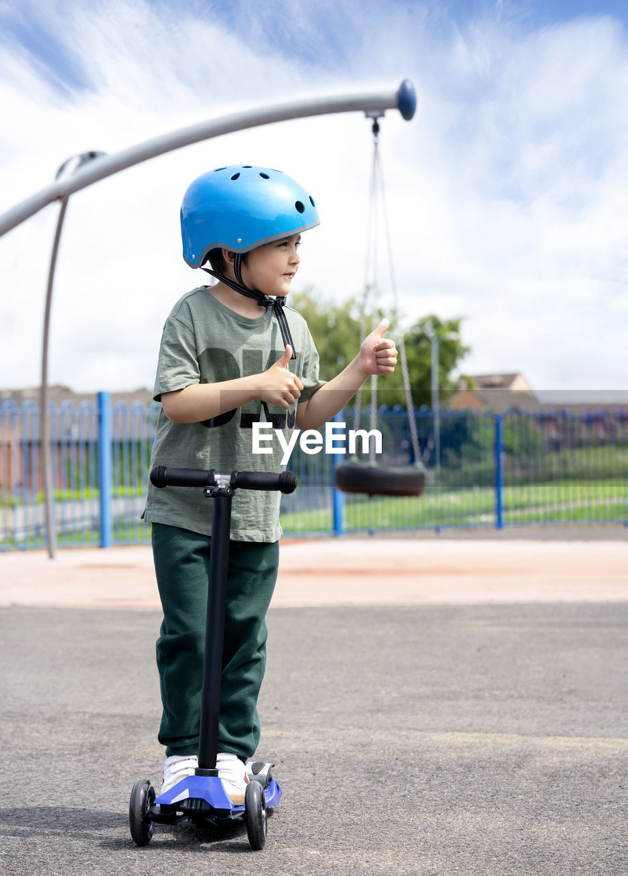 Full length of boy gesturing while standing on push scooter