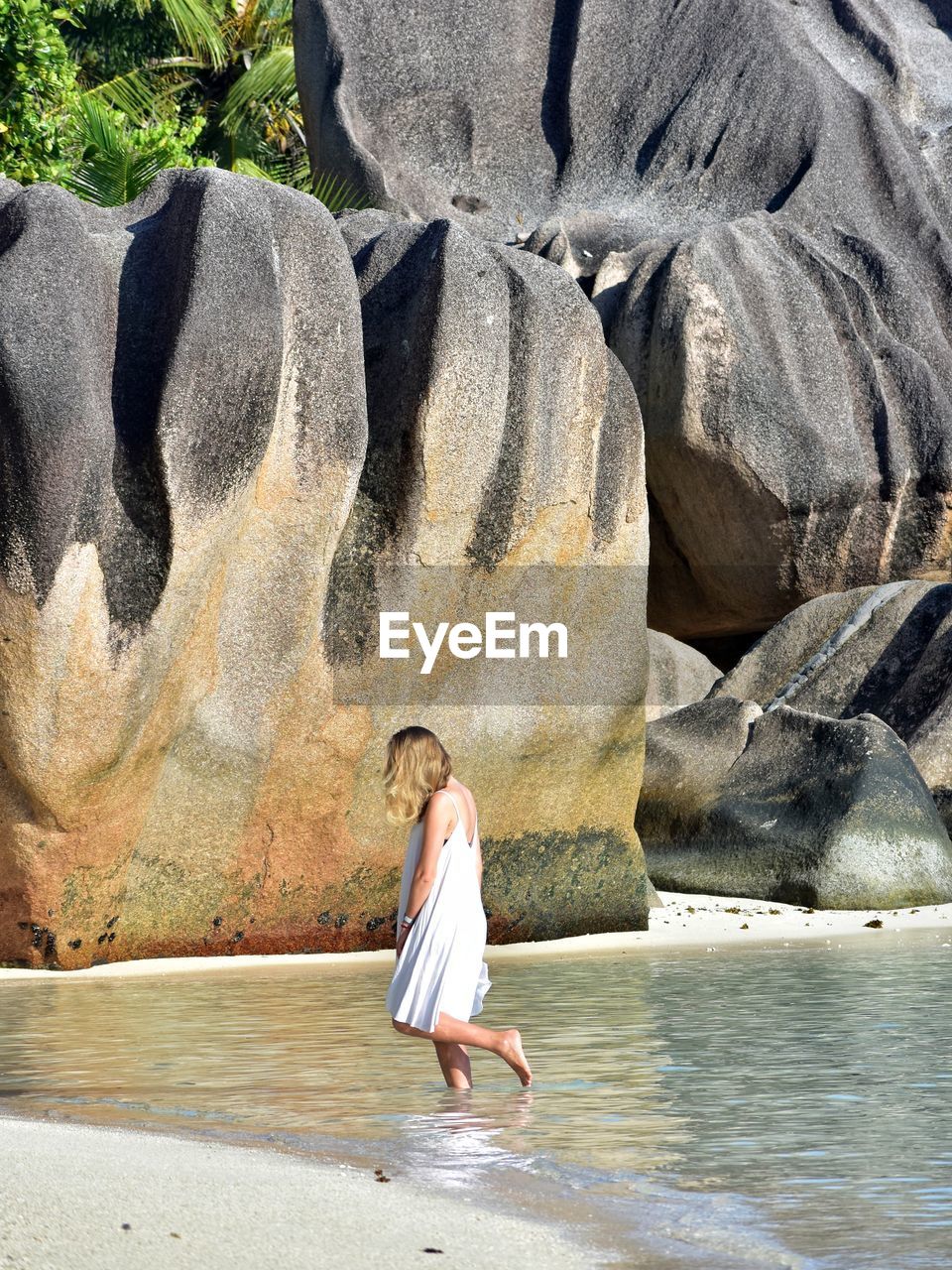 Side view of woman on beach against rock formation