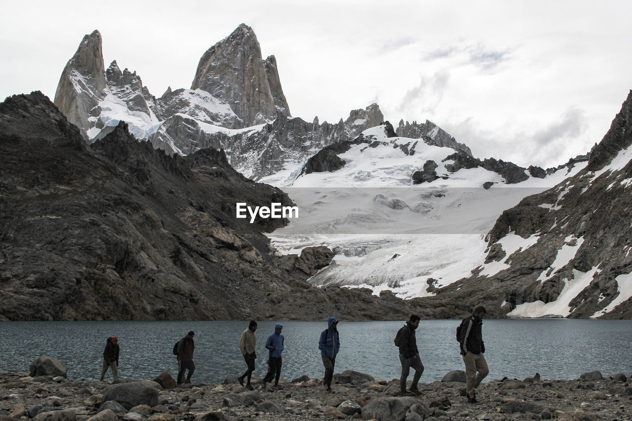 PEOPLE ON SNOW COVERED LAND AGAINST SKY