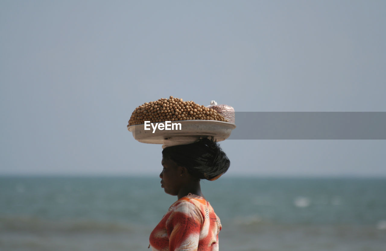 MIDSECTION OF PERSON HOLDING UMBRELLA AGAINST SEA