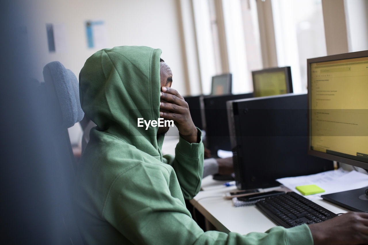 Side view of tired trainee covering eyes while working at office