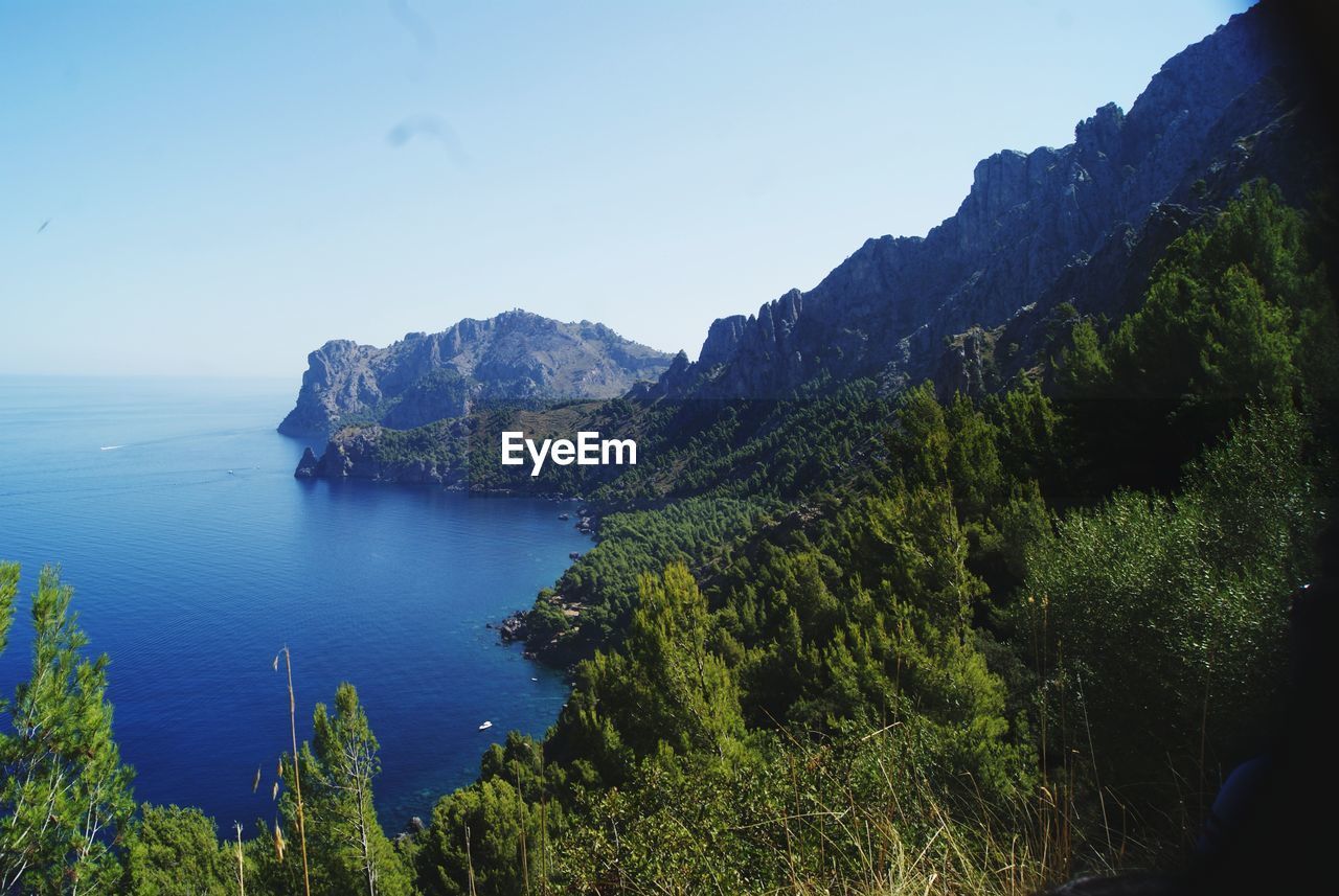 Scenic view of sea and mountains against clear blue sky