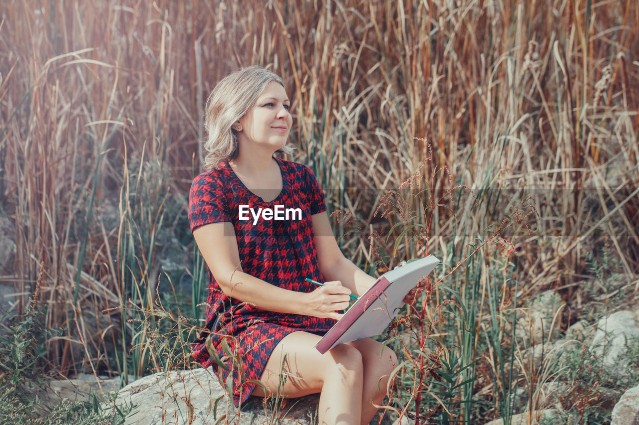 Woman drawing while sitting on grass