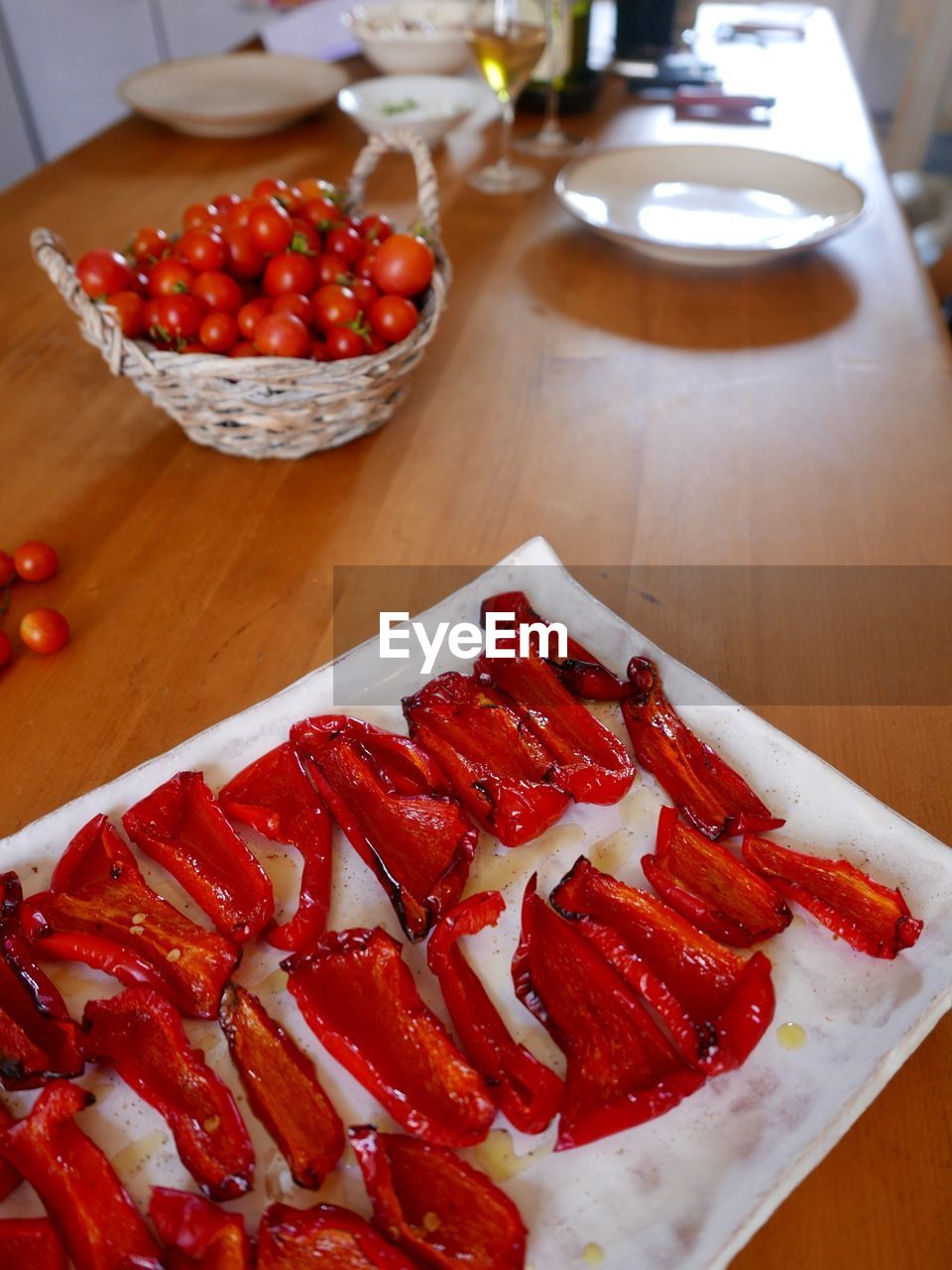 High angle view of fresh sliced red bell peppers with cherry tomatoes in basket on table