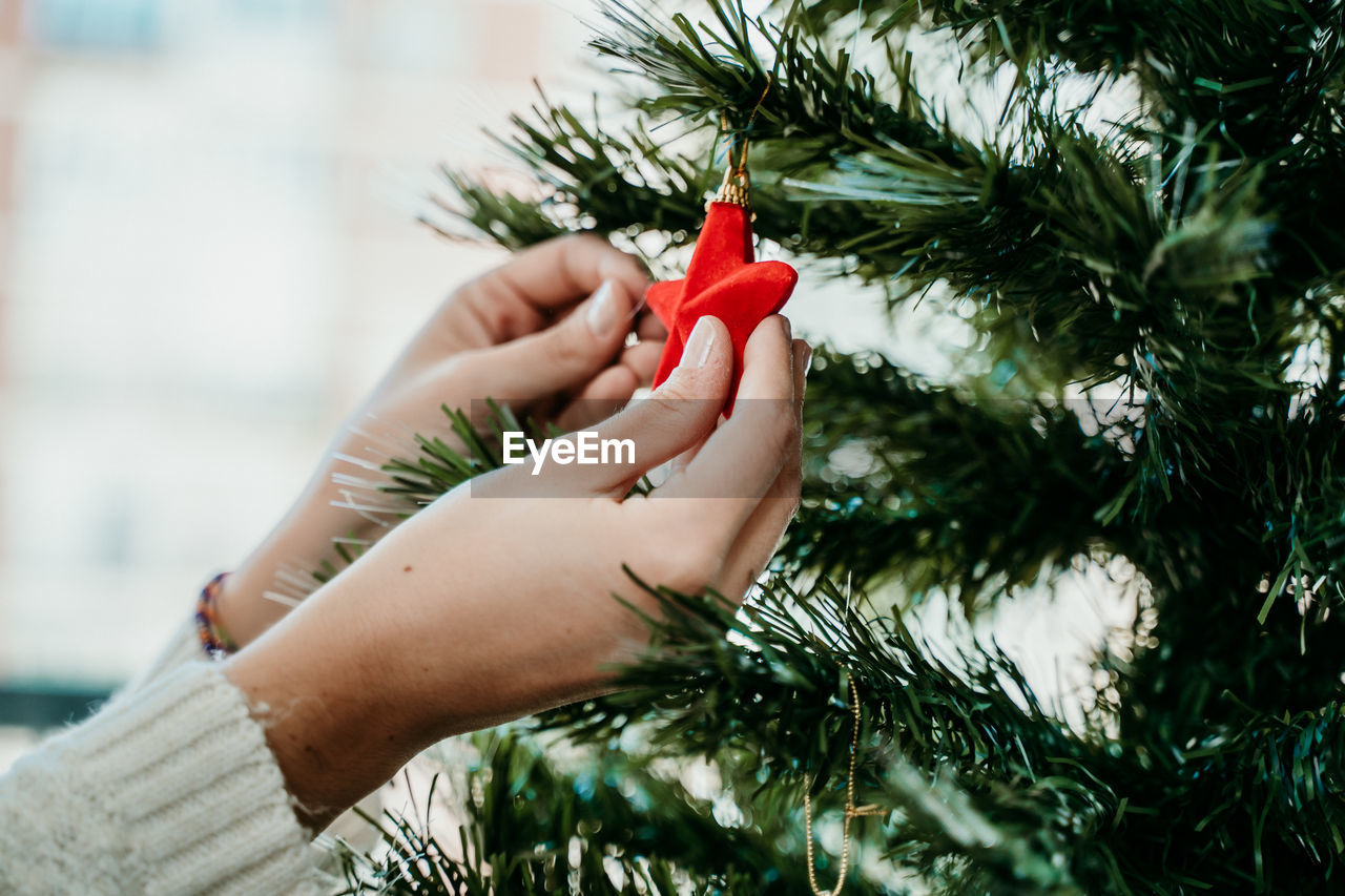 Close-up of woman decorating christmas tree at home