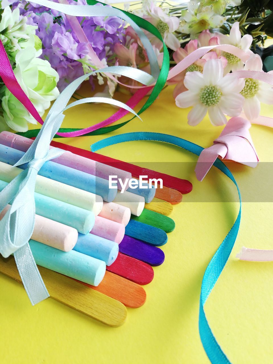 High angle view of multi colored chalks by flowers on table