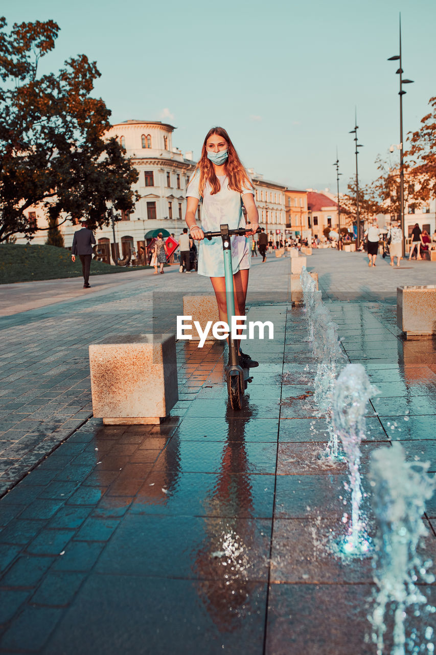 Young woman riding an electric scooter in the city center. woman wearing the face mask