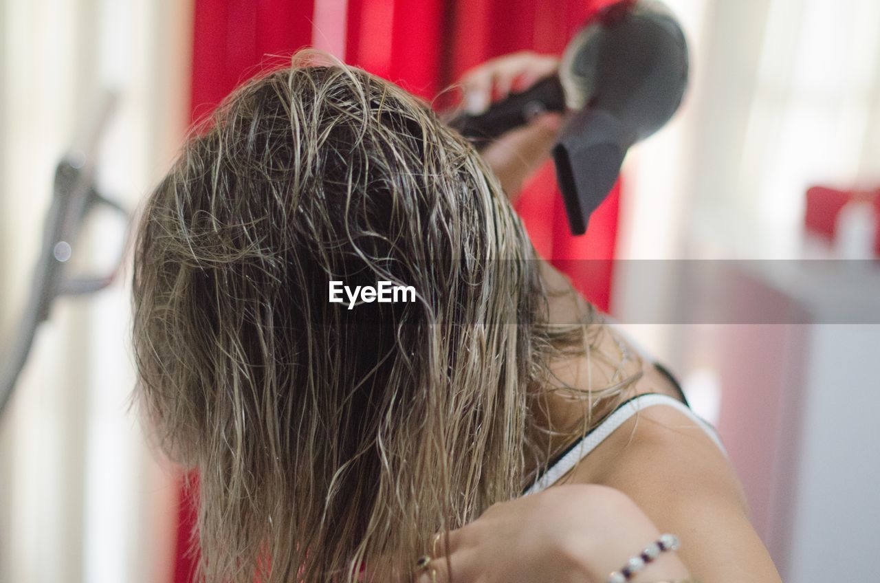 Close-up of woman drying hair with dryer