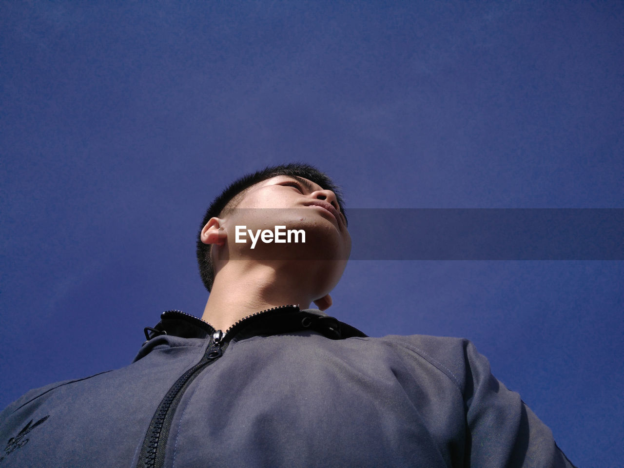 LOW ANGLE PORTRAIT OF YOUNG MAN AGAINST SKY