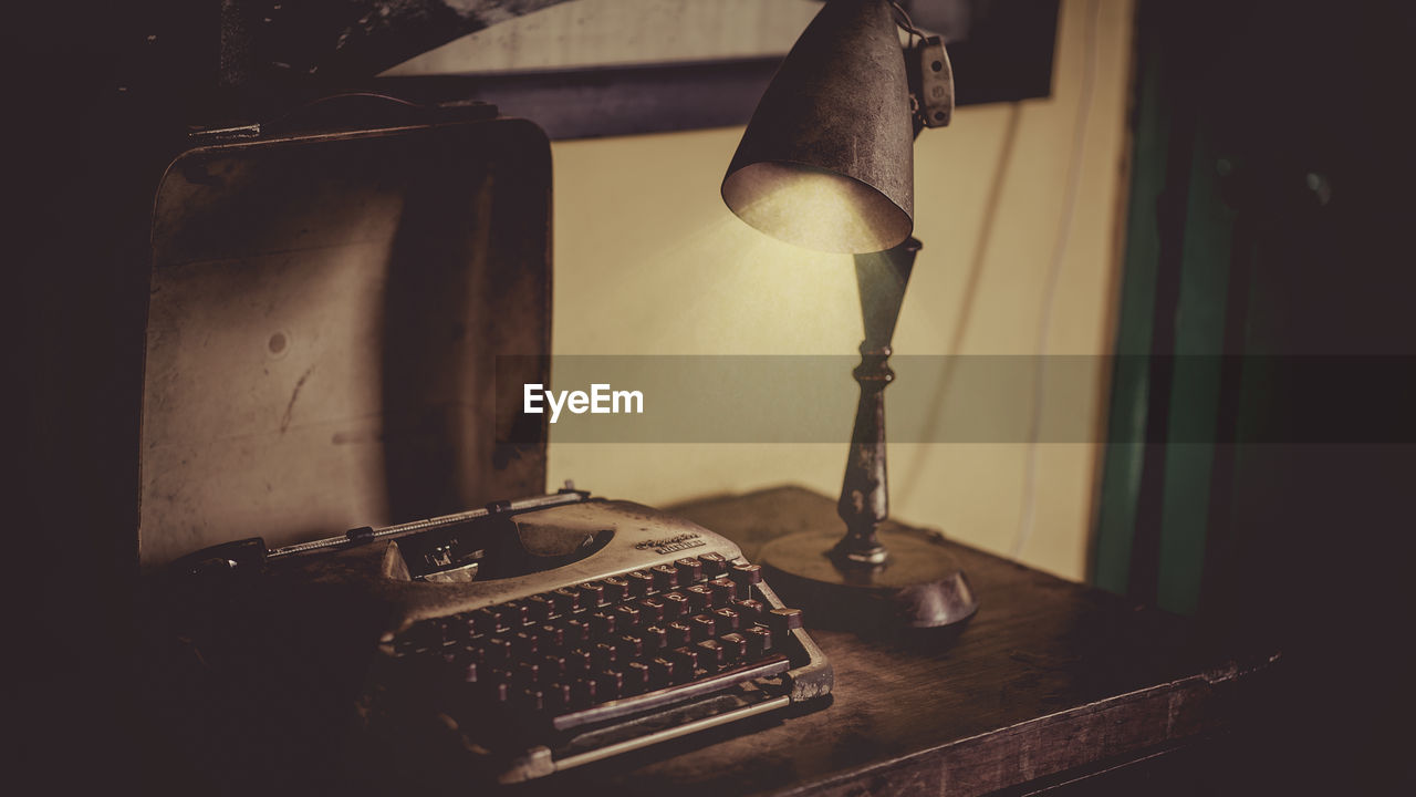 Close-up of old lamp and typewriter on table