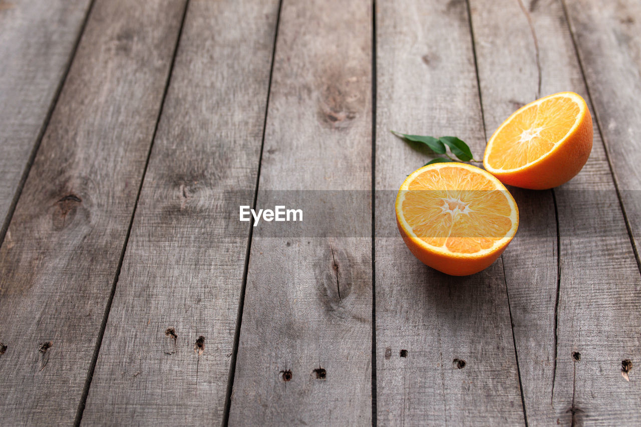 Fresh orange fruit halves or cuts with green leaf on old wooden background table. high quality photo