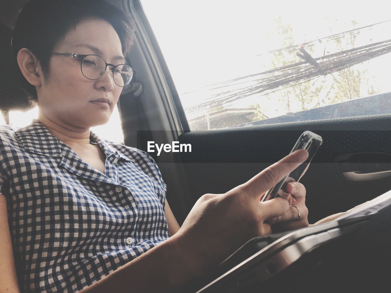 Low angle view of mature woman using mobile phone while sitting in car