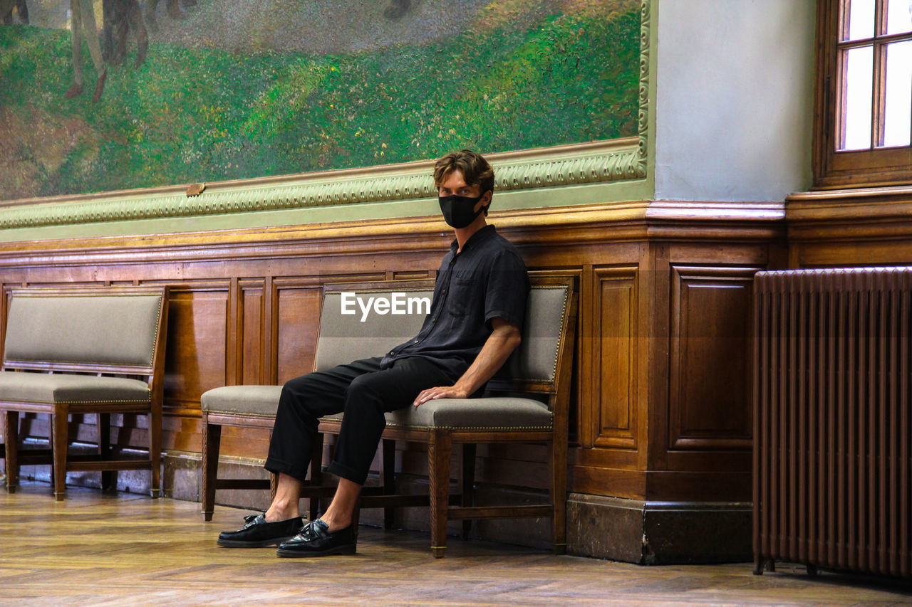 PORTRAIT OF YOUNG WOMAN SITTING ON SEAT