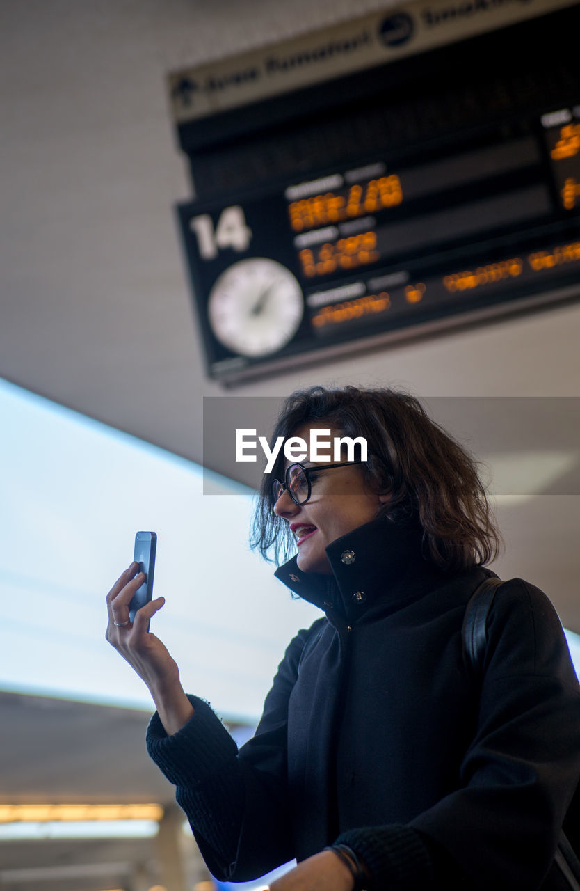 YOUNG WOMAN USING MOBILE PHONE AT CAMERA