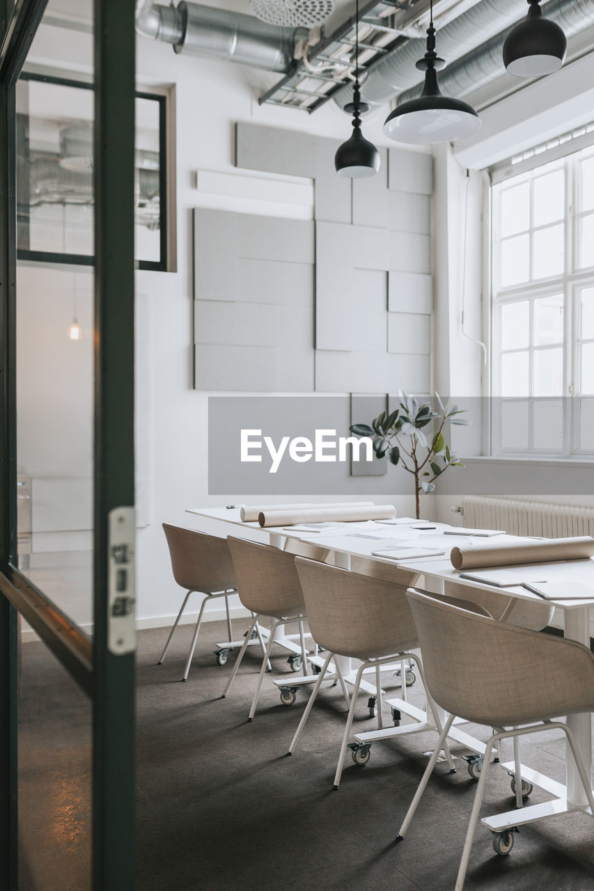 Chairs and tables arranged in empty meeting room at office