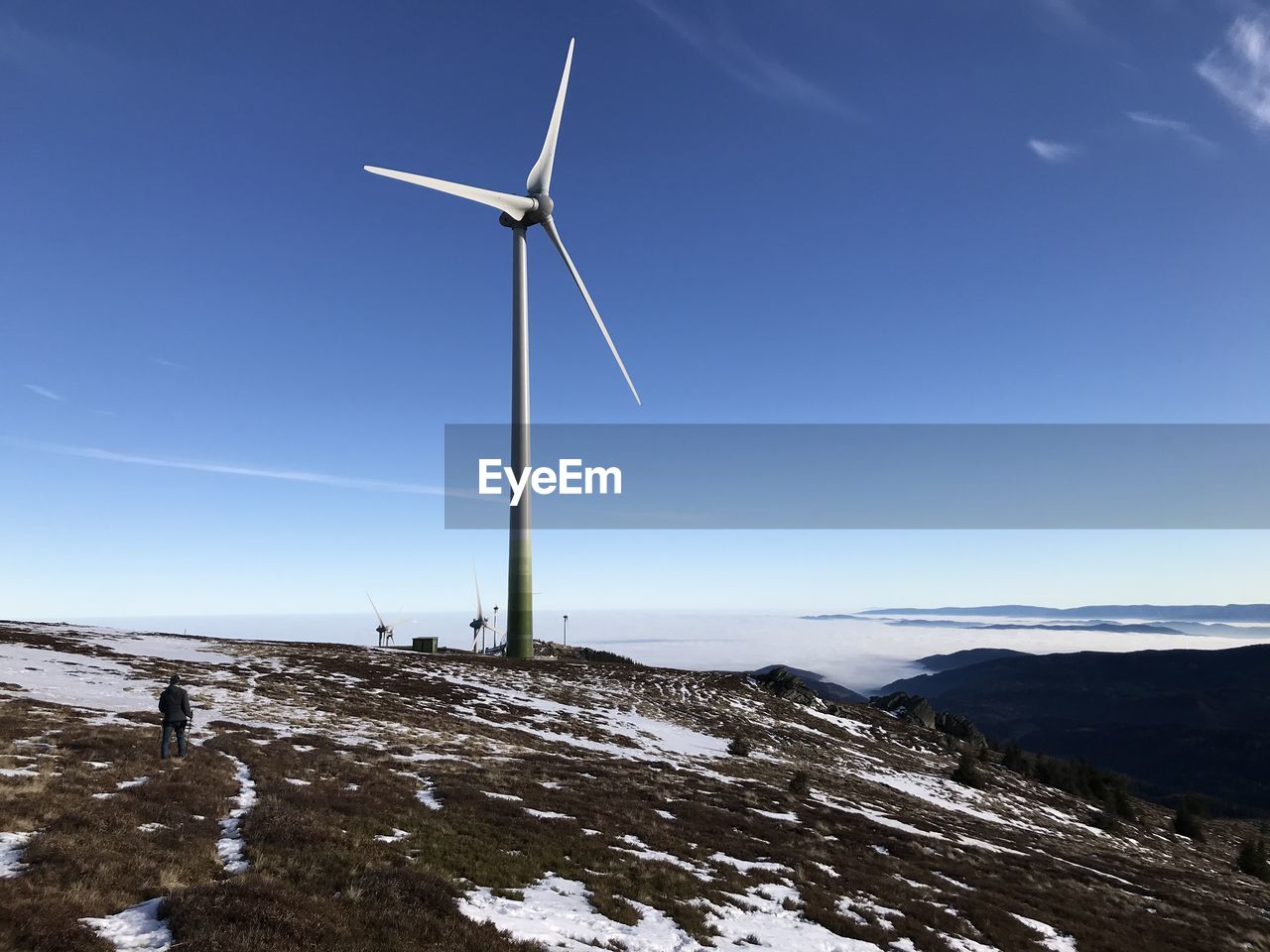WIND TURBINES ON SNOWCAPPED MOUNTAIN AGAINST SKY