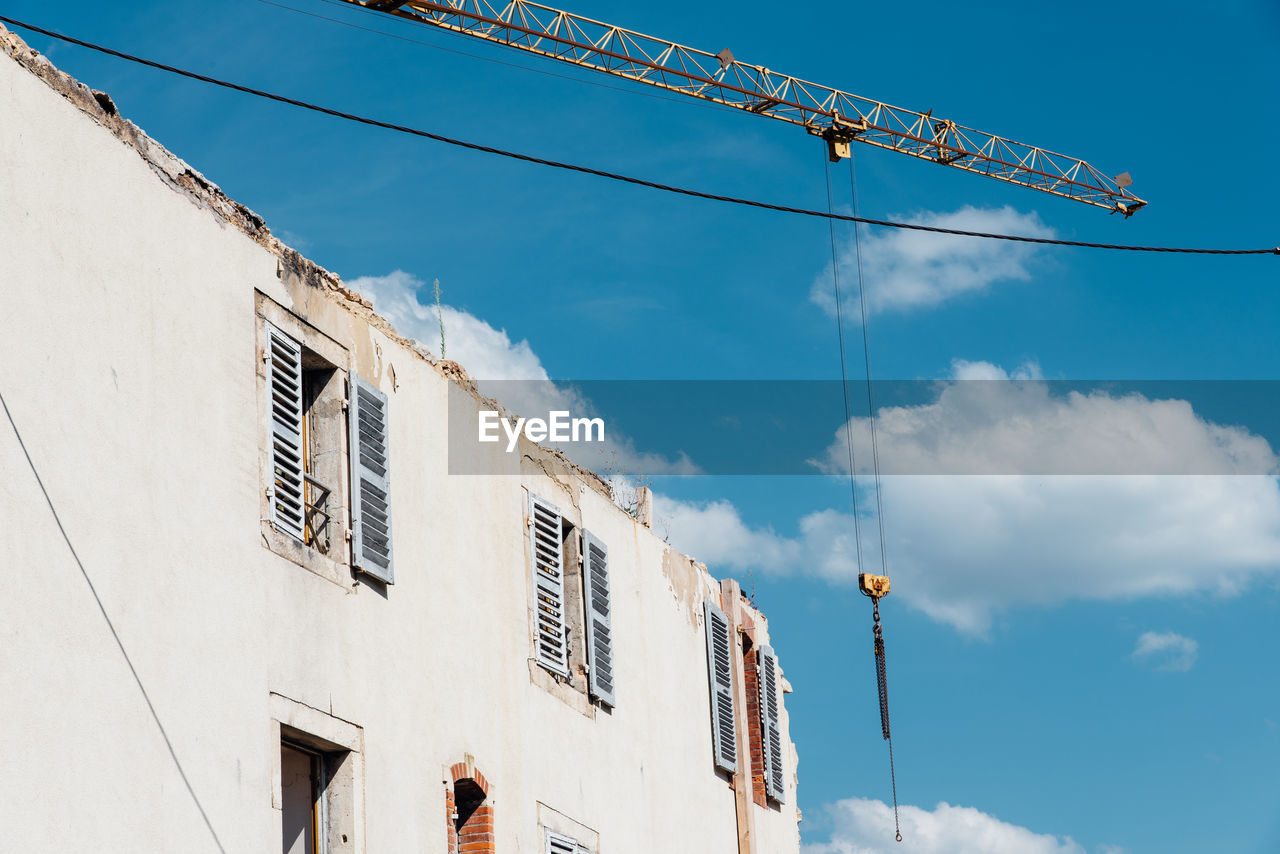 Low angle view of demolition building against sky. a crane demolishing a building 