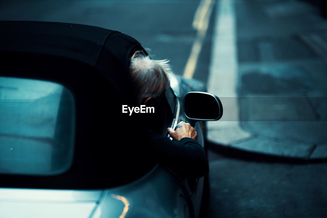 Rear view of man leaning out of car window