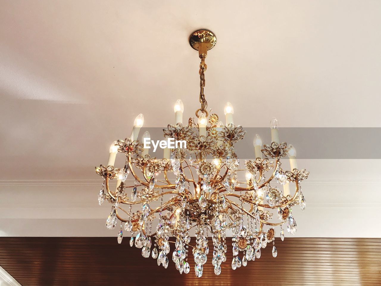 LOW ANGLE VIEW OF ILLUMINATED CHANDELIER HANGING ON WALL